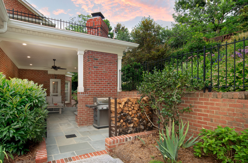Foto di un patio o portico chic di medie dimensioni e dietro casa con un caminetto, pavimentazioni in mattoni e un tetto a sbalzo