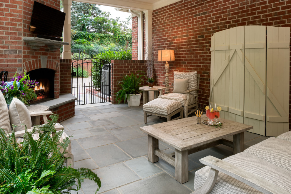 Foto di un patio o portico classico di medie dimensioni e dietro casa con un caminetto, pavimentazioni in mattoni e un tetto a sbalzo