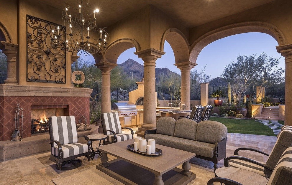 Example of a large tuscan stone patio design in Albuquerque with a fireplace