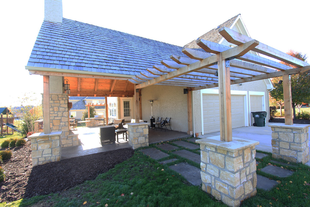 Cette photo montre une grande terrasse arrière tendance avec un foyer extérieur, du béton estampé et une extension de toiture.