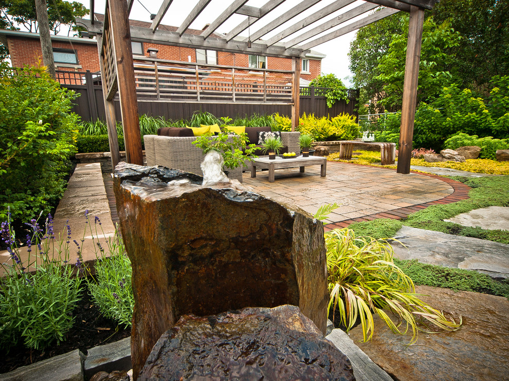 Modelo de patio contemporáneo pequeño en patio trasero con fuente, adoquines de ladrillo y pérgola
