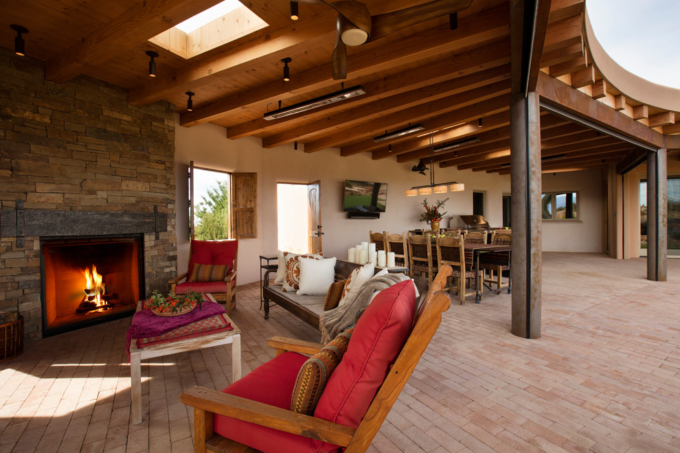 Immagine di un grande patio o portico design dietro casa con pavimentazioni in mattoni, un tetto a sbalzo e un caminetto