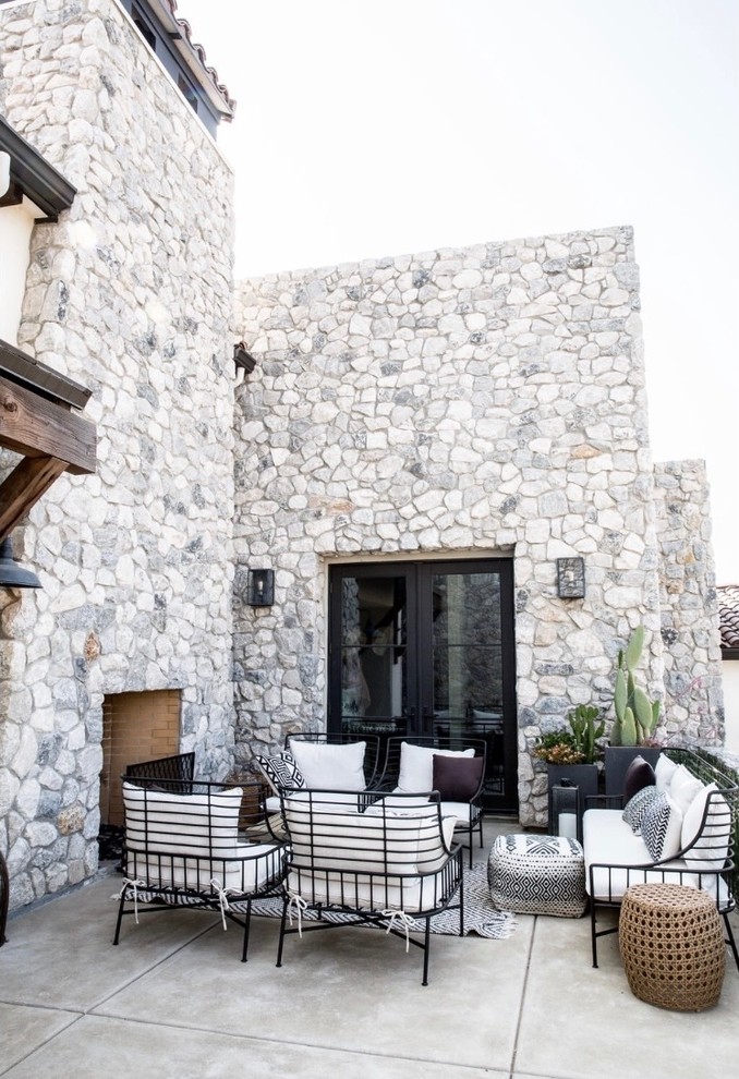 Foto di un patio o portico mediterraneo dietro casa con un caminetto, lastre di cemento e nessuna copertura