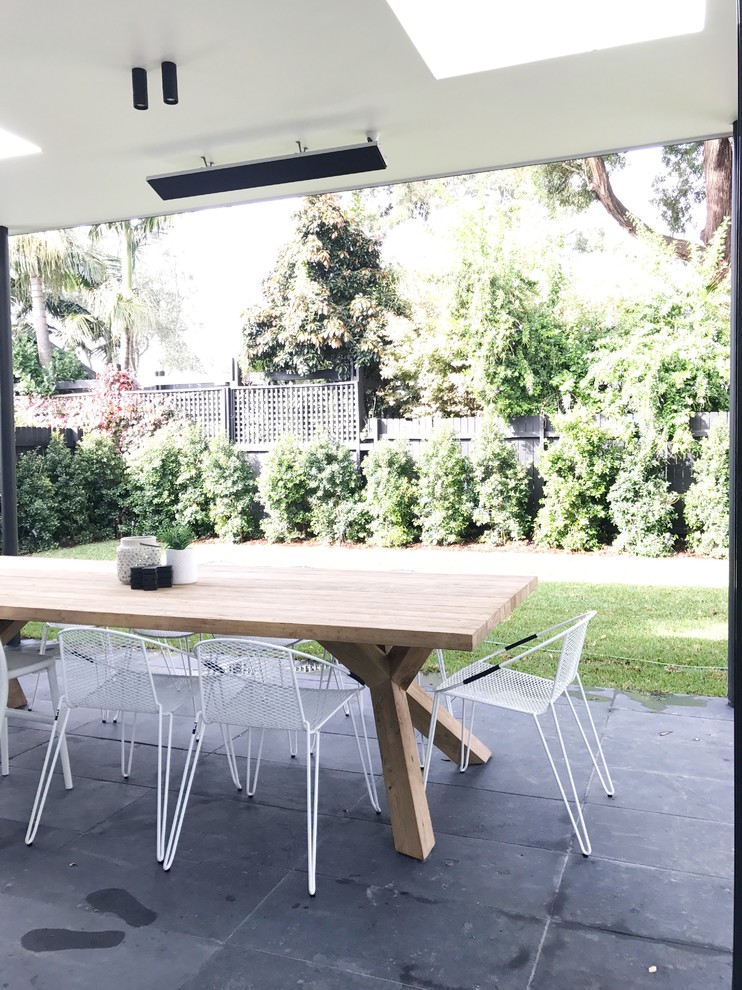 This is an example of a large scandi back patio in Sydney with natural stone paving.