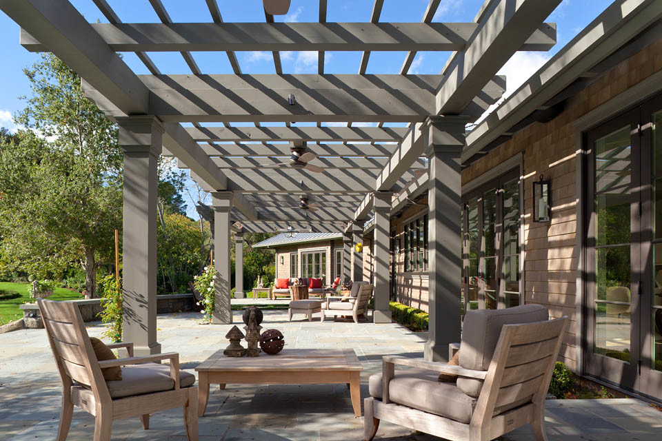Immagine di un grande patio o portico contemporaneo dietro casa con pavimentazioni in pietra naturale e una pergola