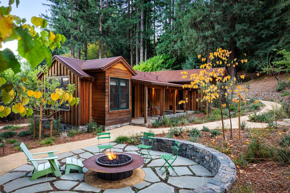 Example of a mid-sized mountain style front yard stone patio design in San Francisco with a fire pit and no cover