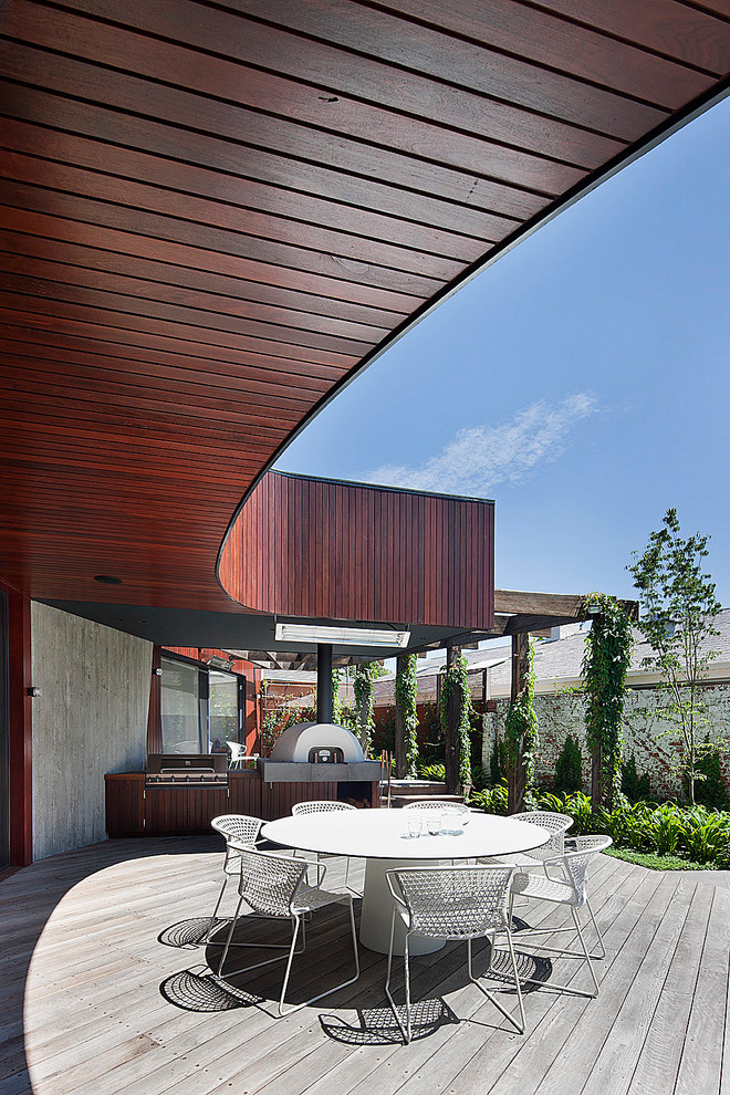 Modelo de patio contemporáneo grande en anexo de casas con cocina exterior y entablado