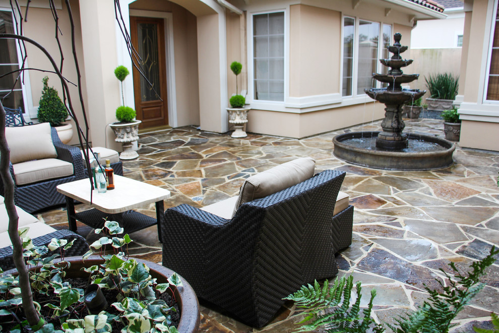 Ejemplo de patio de estilo americano de tamaño medio sin cubierta en patio con fuente y adoquines de piedra natural