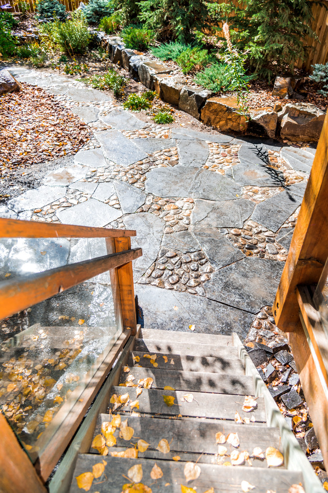 Small romantic back patio in Calgary with a fire feature, natural stone paving and no cover.