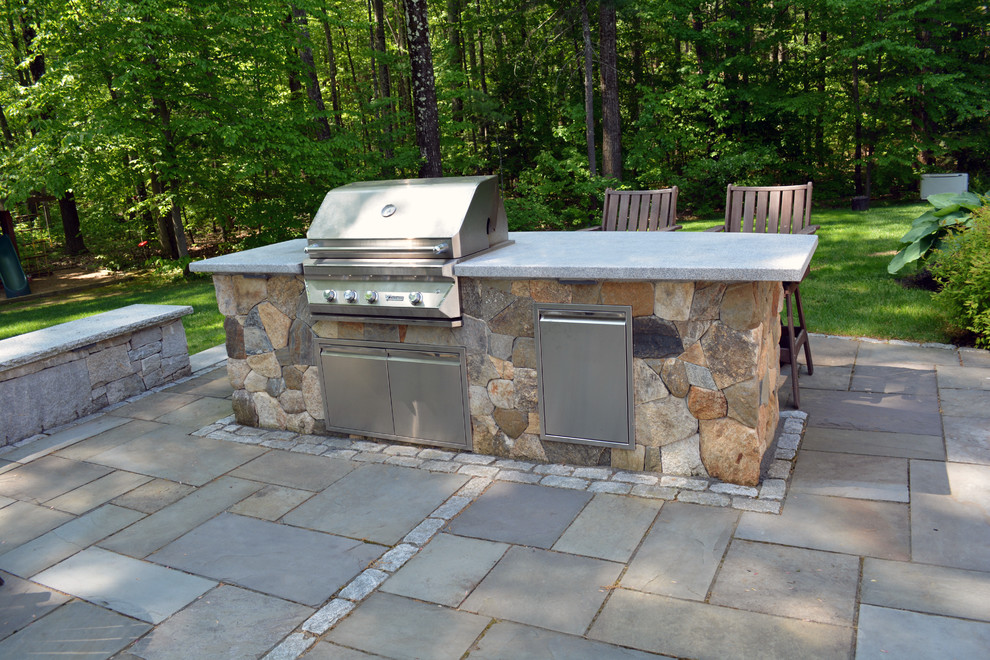 Idée de décoration pour une terrasse arrière chalet avec des pavés en pierre naturelle et une cuisine d'été.