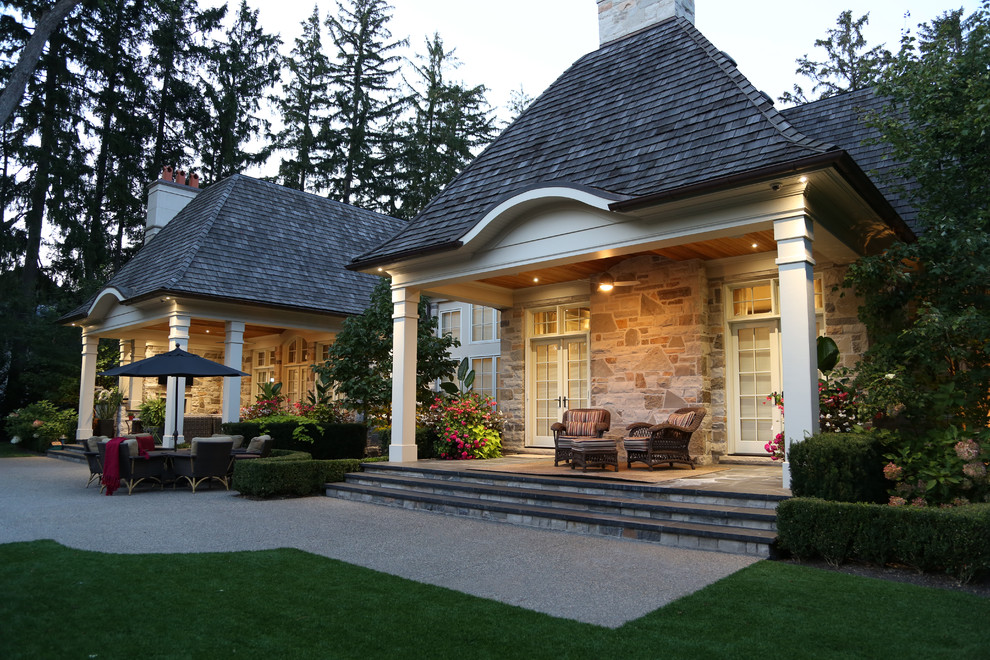 Immagine di un patio o portico chic dietro casa con pavimentazioni in pietra naturale e un tetto a sbalzo