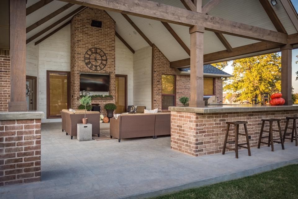 Cette image montre une grande terrasse arrière traditionnelle avec un foyer extérieur, une dalle de béton et une extension de toiture.