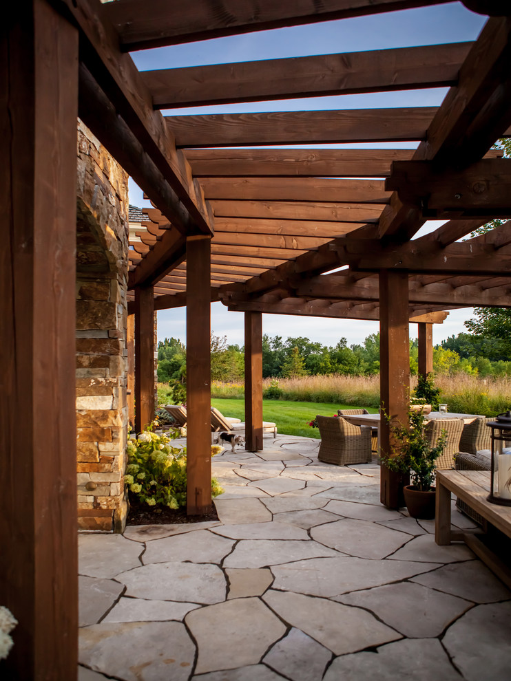 Inspiration for a large rustic backyard stone patio remodel in Minneapolis with a pergola