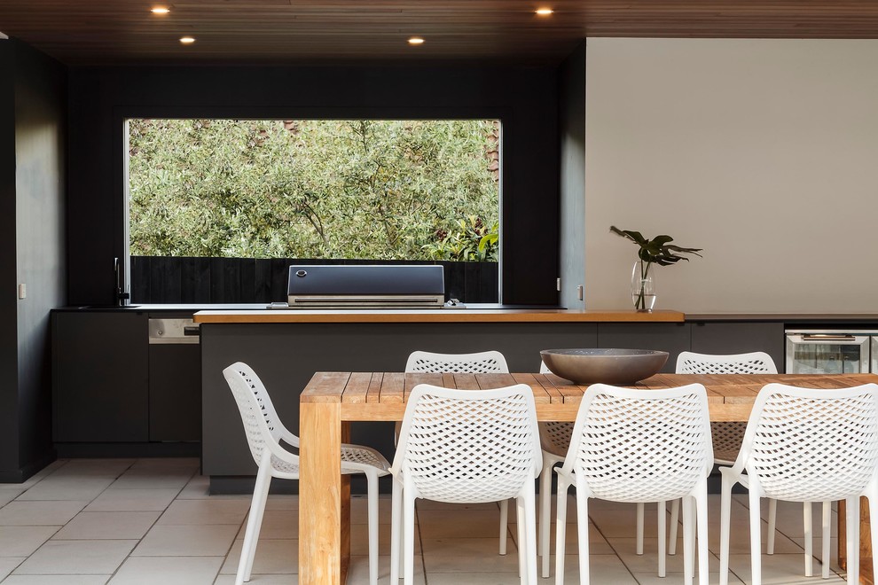 Aménagement d'une terrasse moderne avec une cuisine d'été, du carrelage et une extension de toiture.