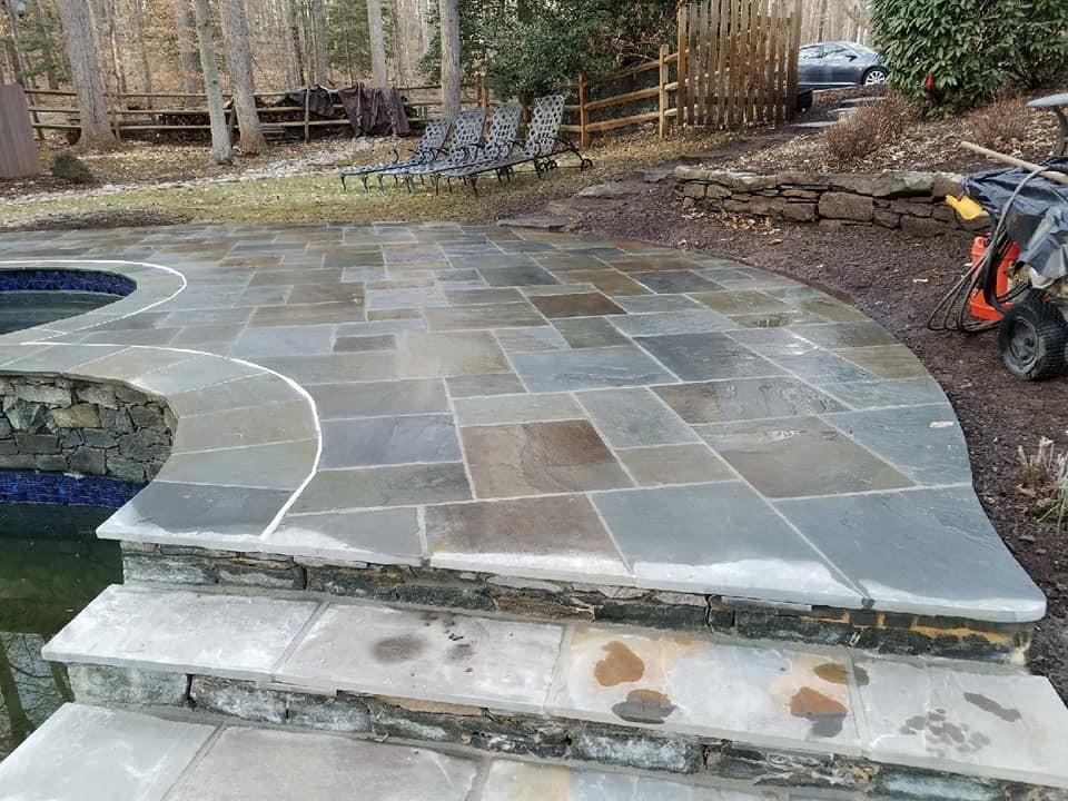 Expansive traditional back patio in Other with a water feature, natural stone paving and no cover.