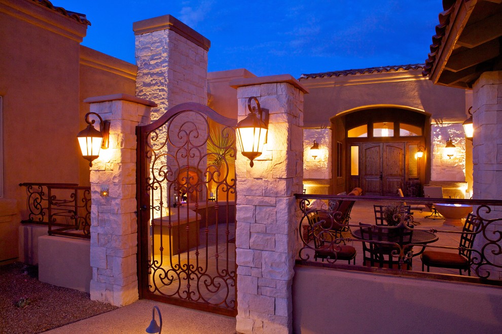 Example of a tuscan courtyard stone patio design in Phoenix with a fire pit and no cover