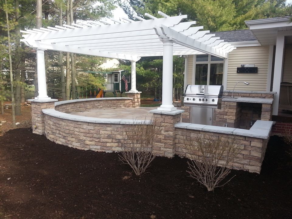 Example of a large classic backyard stone patio design in Milwaukee with a pergola