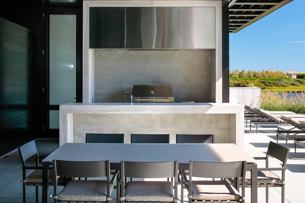 Cette image montre une terrasse arrière minimaliste de taille moyenne avec une cuisine d'été et une extension de toiture.