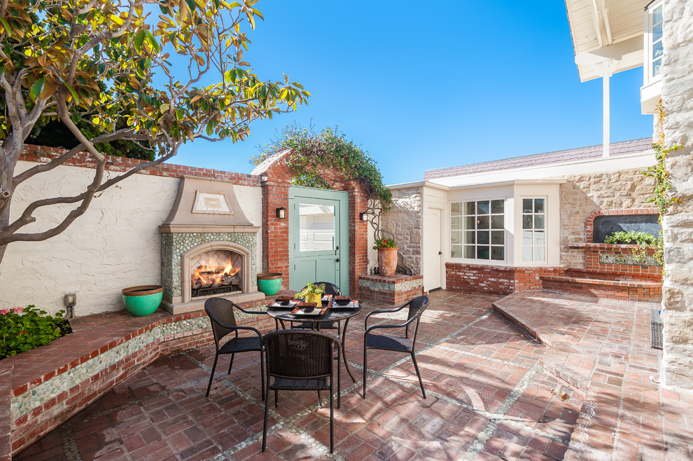 Design ideas for a classic front patio in Orange County with brick paving and a fireplace.
