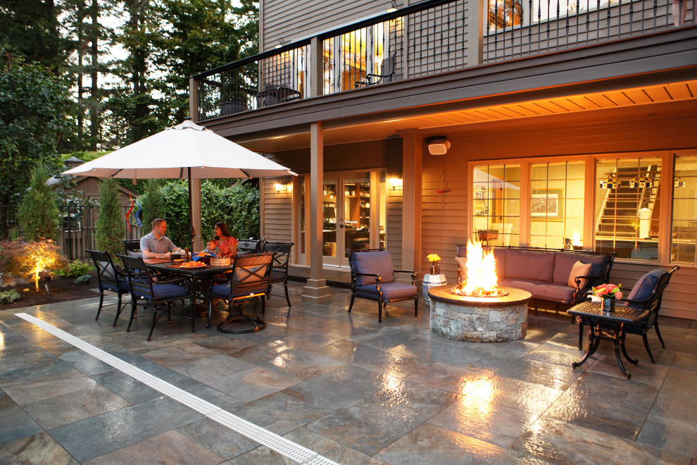 Photo of a medium sized contemporary back patio in Seattle with natural stone paving, a fire feature and an awning.