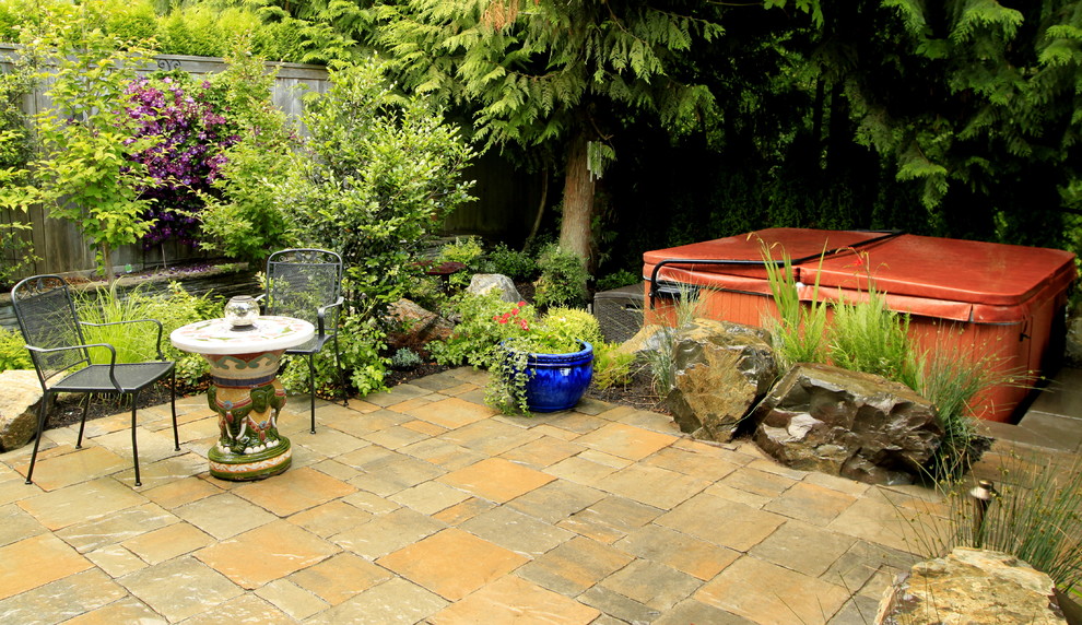 This is an example of a medium sized traditional back patio in Seattle with natural stone paving and no cover.