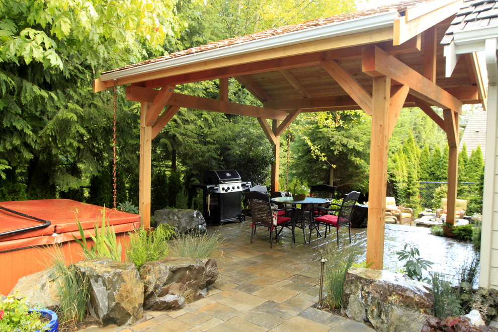 Réalisation d'une terrasse arrière tradition de taille moyenne avec des pavés en pierre naturelle et un gazebo ou pavillon.
