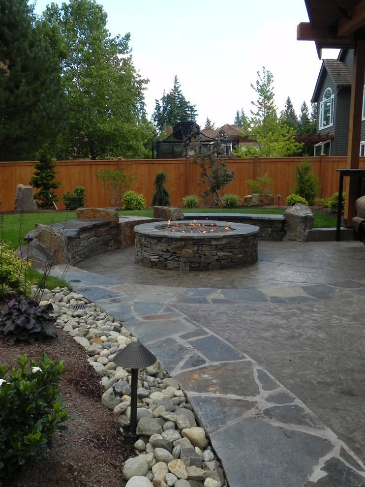 Medium sized contemporary back patio in Seattle with a fire feature and stamped concrete.