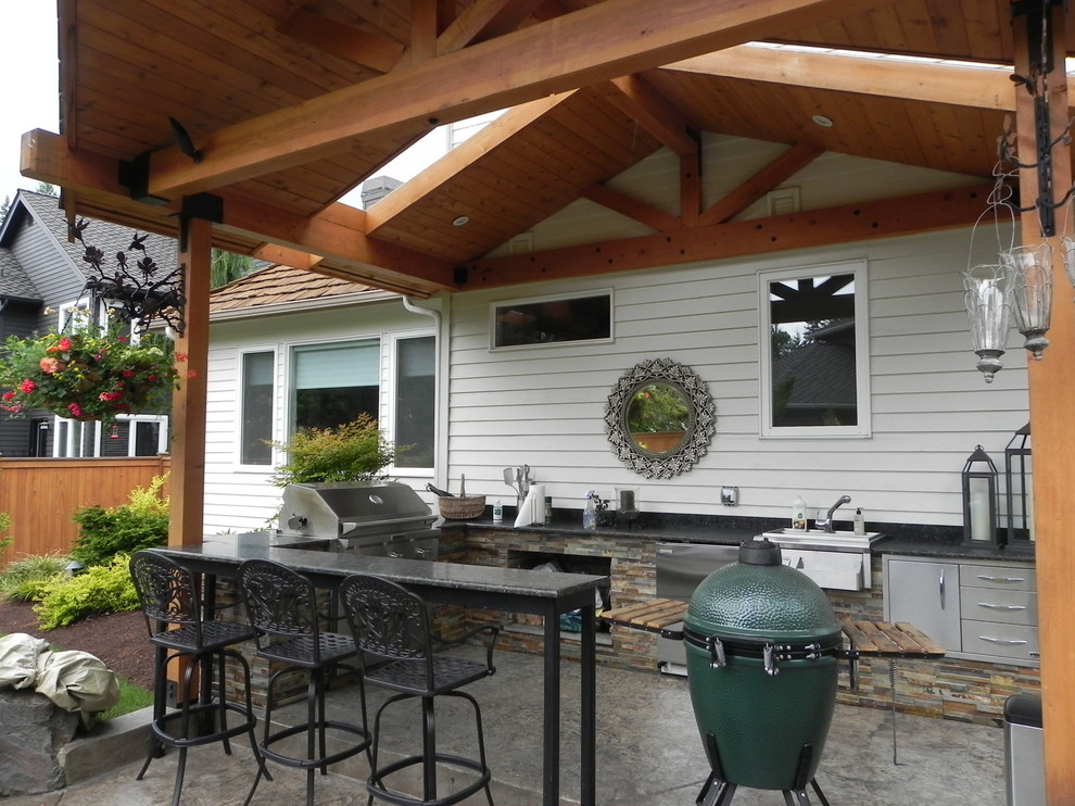 Esempio di un patio o portico boho chic di medie dimensioni e dietro casa con cemento stampato e un tetto a sbalzo