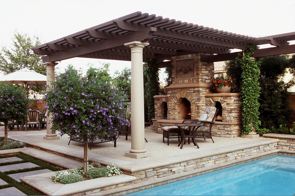 Immagine di un patio o portico mediterraneo di medie dimensioni e dietro casa con un focolare, lastre di cemento e una pergola