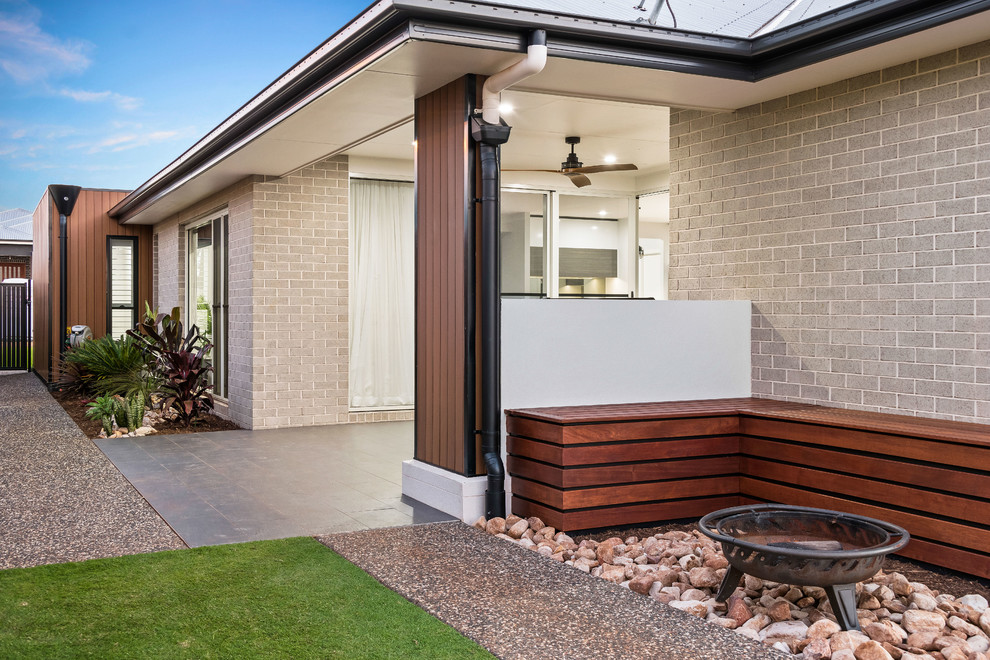 Cette photo montre une terrasse arrière tendance de taille moyenne avec un foyer extérieur, du carrelage et une extension de toiture.