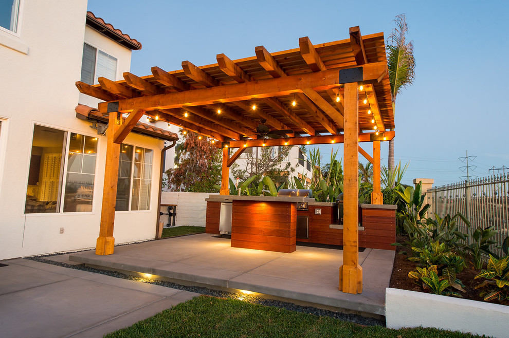Exemple d'une terrasse arrière tendance avec un foyer extérieur et une pergola.