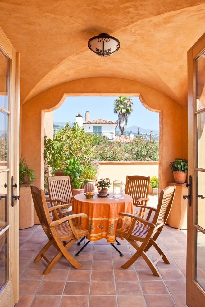 Foto di un patio o portico mediterraneo in cortile e di medie dimensioni con piastrelle e un tetto a sbalzo