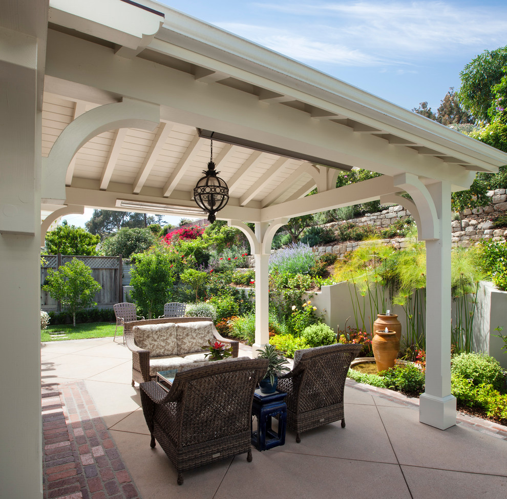 Inspiration pour une terrasse arrière traditionnelle avec des pavés en béton et une extension de toiture.