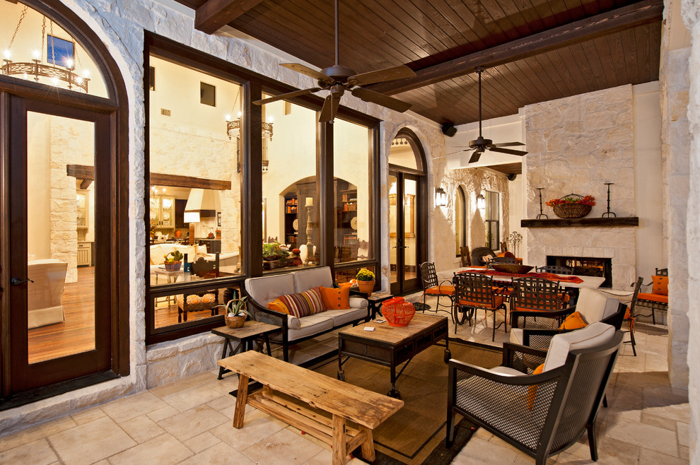 Esempio di un ampio patio o portico mediterraneo dietro casa con un focolare, pavimentazioni in pietra naturale e un tetto a sbalzo