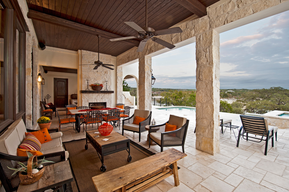 Photo of a large mediterranean back patio in Austin with a fire feature, a roof extension and tiled flooring.