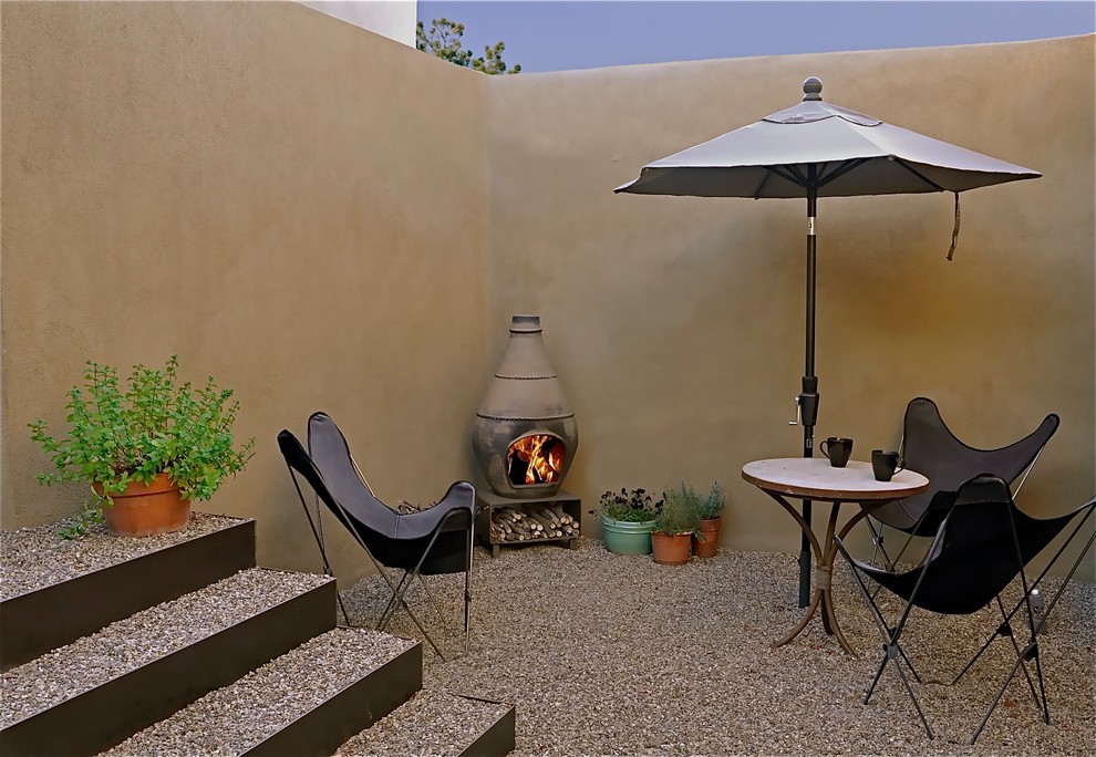 Immagine di un piccolo patio o portico moderno in cortile con un focolare e ghiaia
