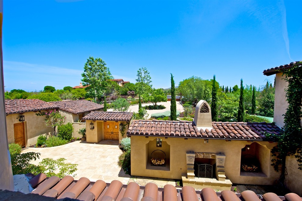 Esempio di un ampio patio o portico mediterraneo in cortile con un focolare, pavimentazioni in pietra naturale e un tetto a sbalzo