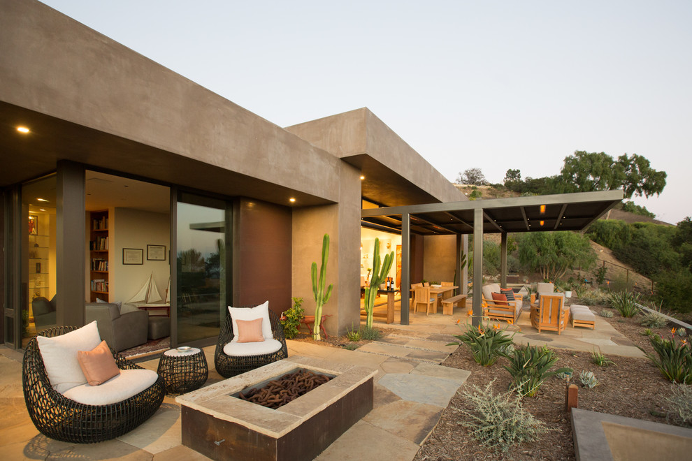 Inspiration for a large back patio in Santa Barbara with a fire feature, natural stone paving and a roof extension.