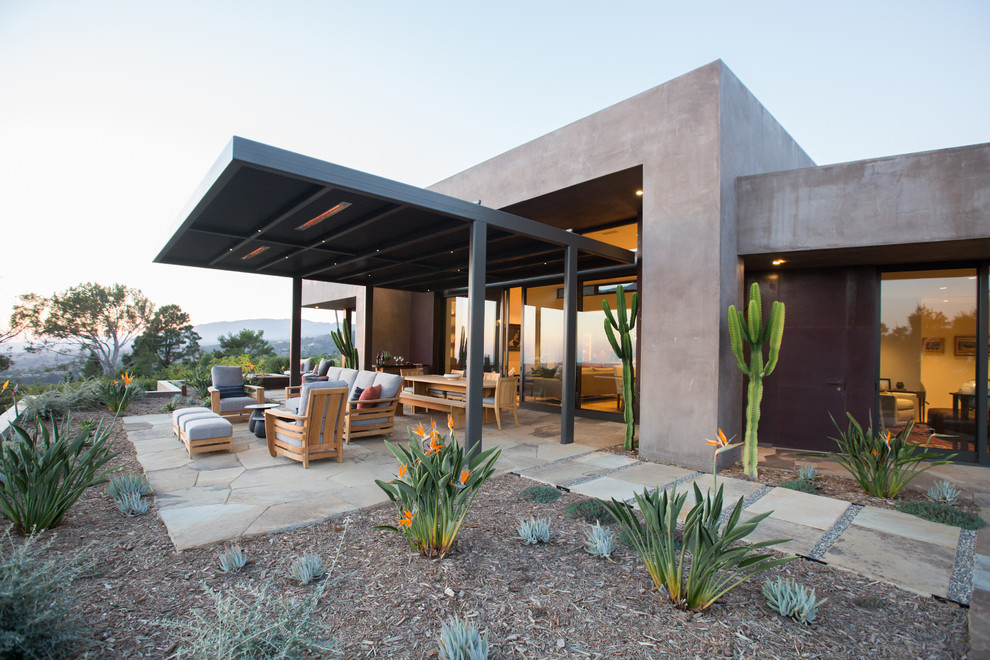 Inspiration pour une grande terrasse arrière sud-ouest américain avec un foyer extérieur, des pavés en pierre naturelle et une extension de toiture.