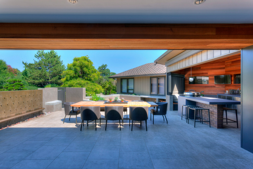 Inspiration pour une terrasse design de taille moyenne avec une cuisine d'été, une cour, du carrelage et une extension de toiture.
