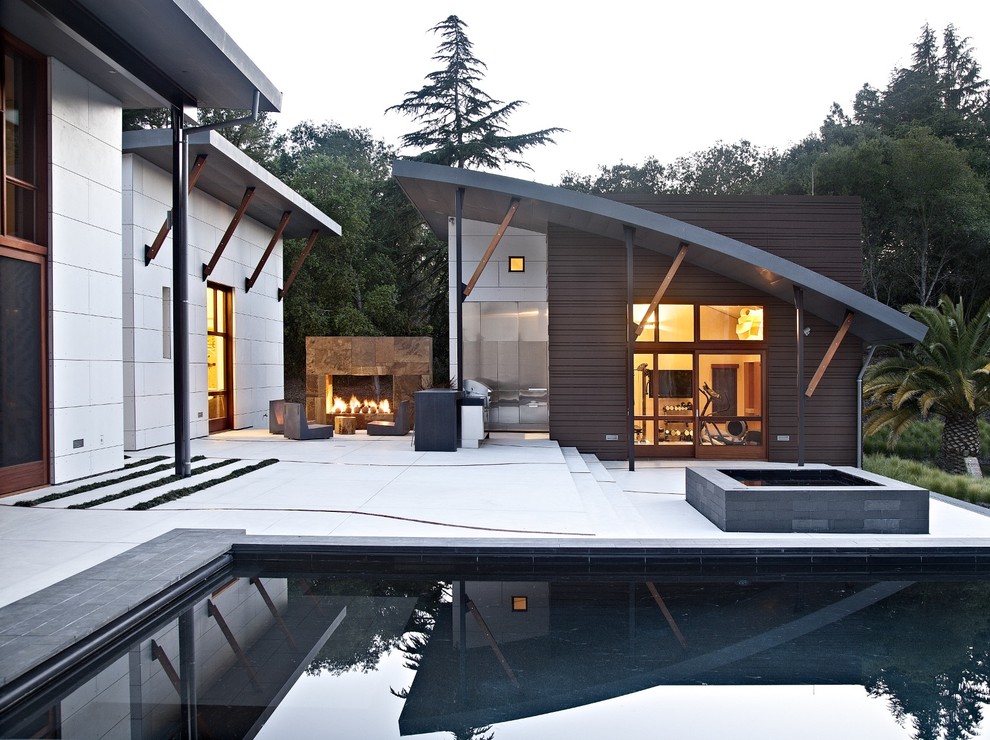Diseño de patio contemporáneo grande sin cubierta en patio trasero con brasero y losas de hormigón