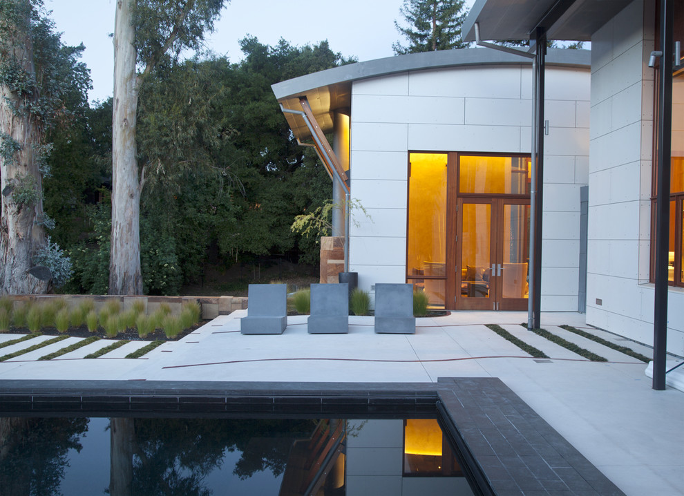 This is an example of a large contemporary back patio in San Francisco with a fire feature, concrete slabs and no cover.