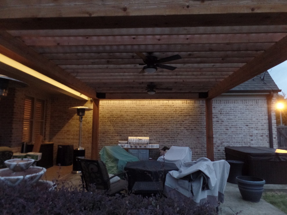 Photo of a large rustic back patio in Other with stamped concrete and a pergola.