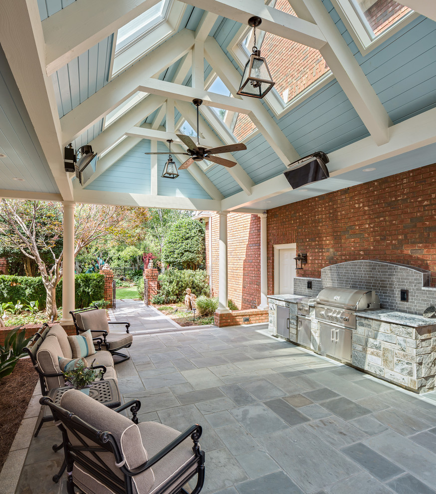 Aménagement d'une terrasse éclectique de taille moyenne avec une cuisine d'été, des pavés en pierre naturelle, une cour et une extension de toiture.