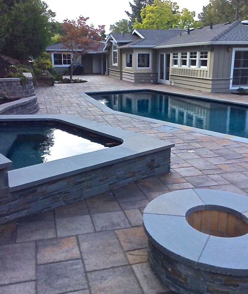 Photo of a large retro back patio in San Francisco with a fire feature and concrete paving.