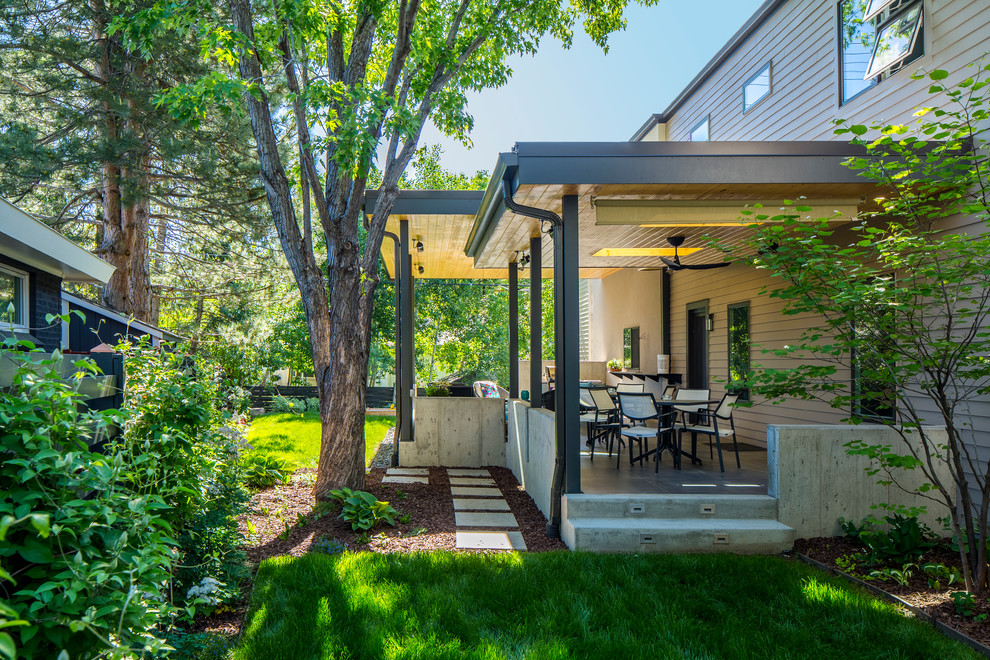 Cette image montre une terrasse arrière design de taille moyenne avec un foyer extérieur, des pavés en béton et une extension de toiture.