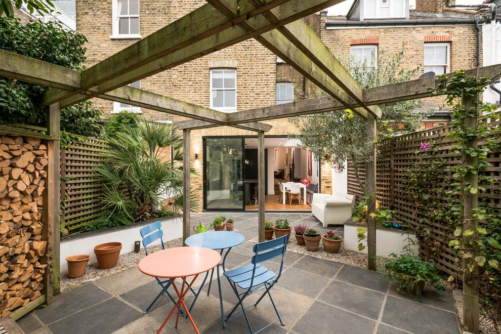 Example of a mid-sized classic backyard patio vertical garden design in London with a pergola