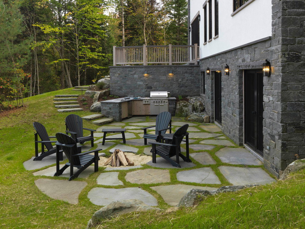 Inspiration pour une grande terrasse arrière traditionnelle avec des pavés en pierre naturelle et aucune couverture.