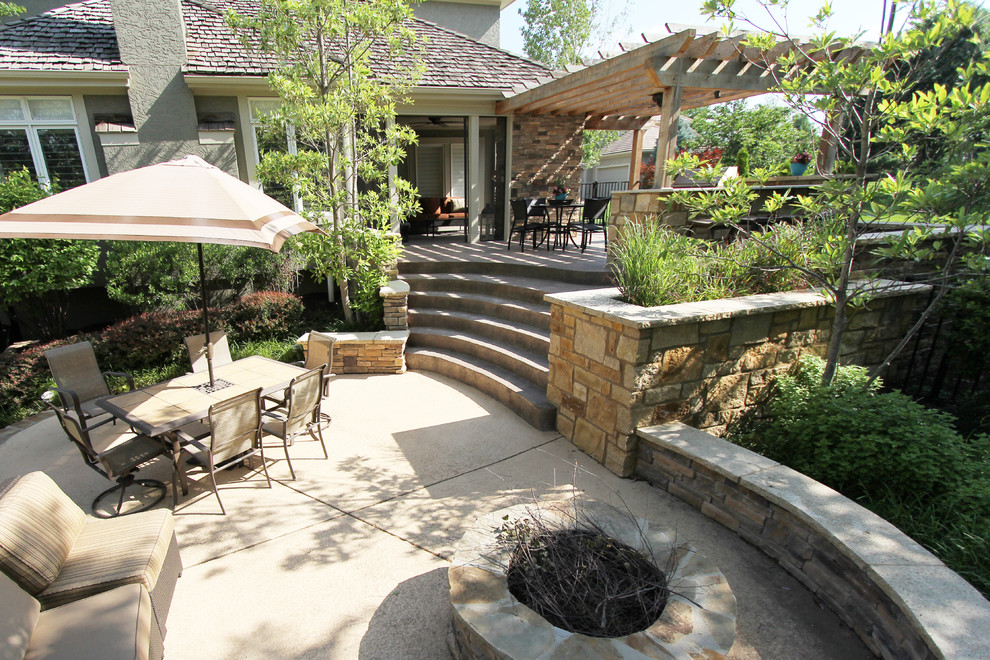Cette image montre une grande terrasse arrière design avec une cuisine d'été, du béton estampé et une pergola.