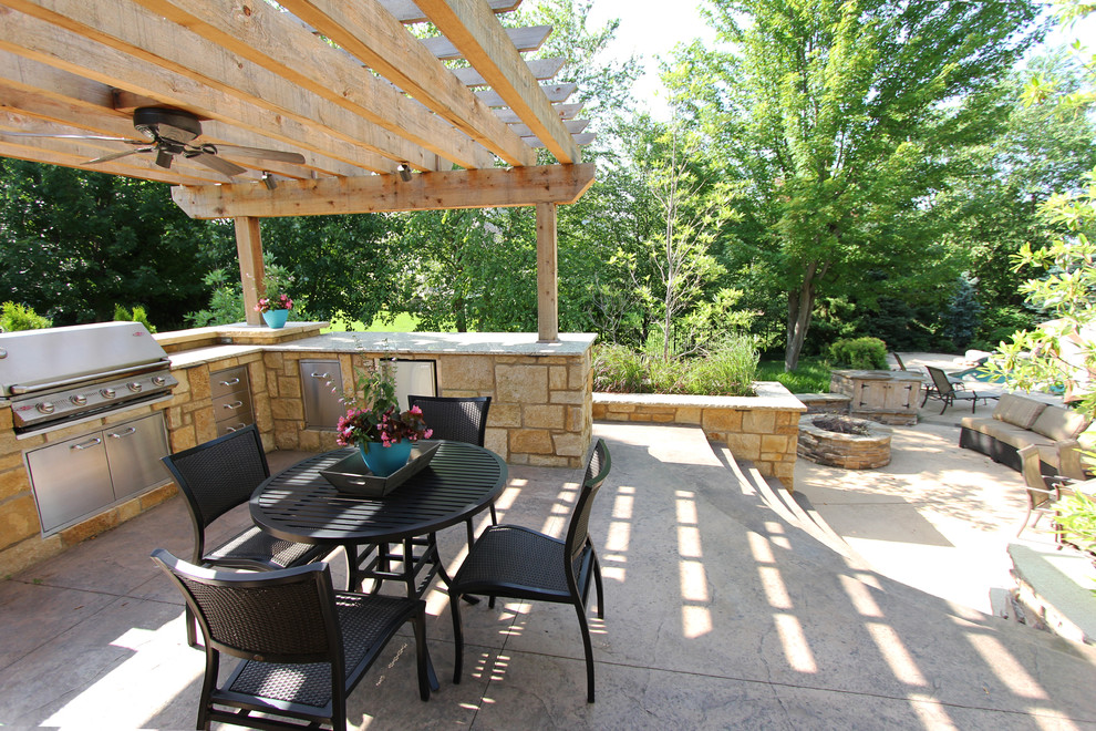 Réalisation d'une grande terrasse arrière design avec une cuisine d'été, du béton estampé et une pergola.